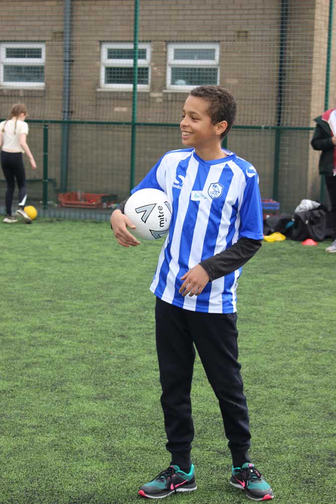 Young boy holding a football smiling