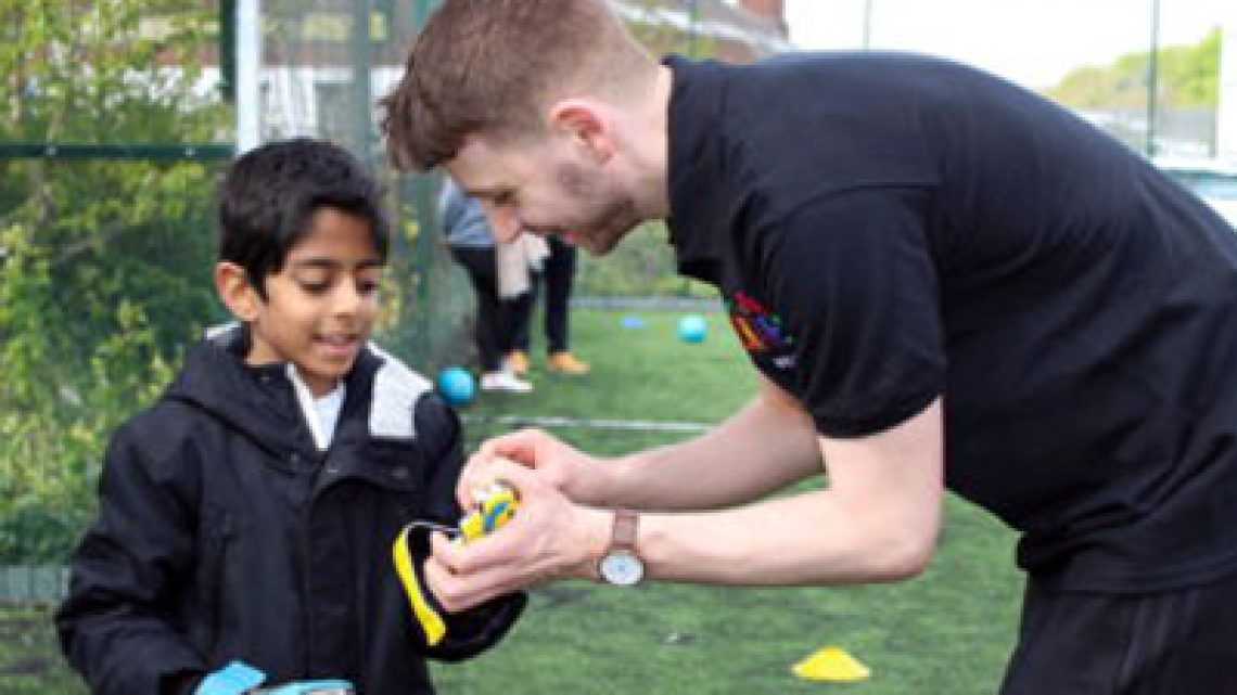 Football instructor helping a young boy with his gloves