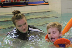 Young child swimming with an instructor