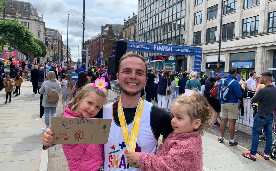 A father in a SNAPS t-shirt celebrating with his two daughters after running the 10k