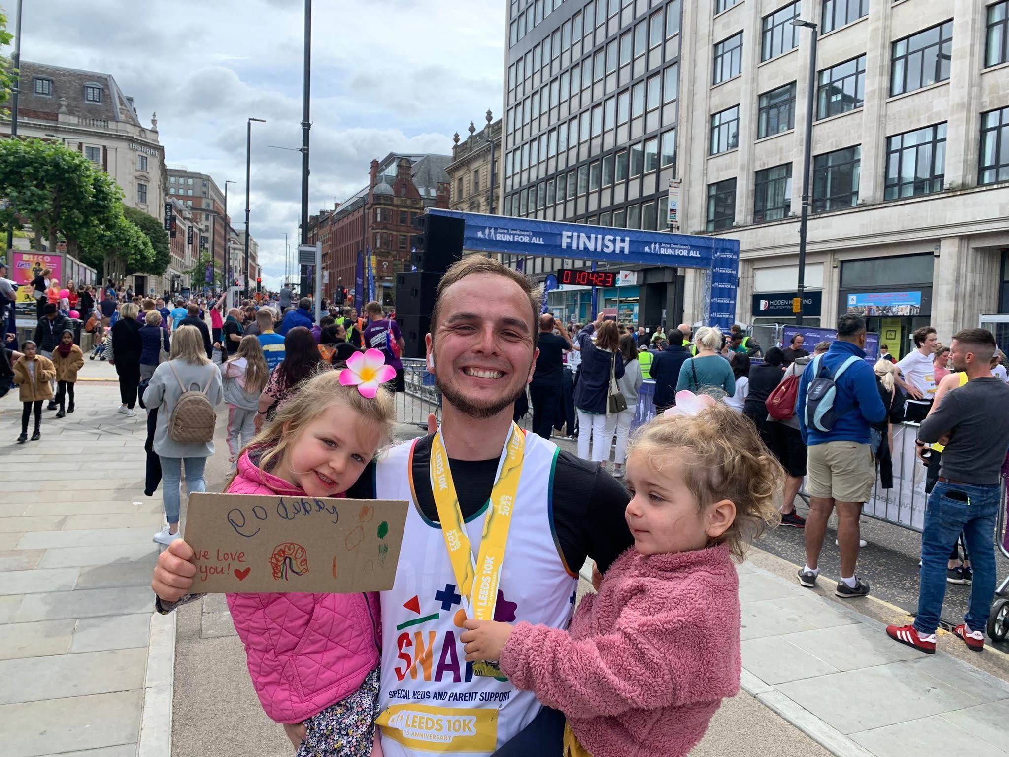 A father in a SNAPS t-shirt celebrating with his two daughters after running the 10k